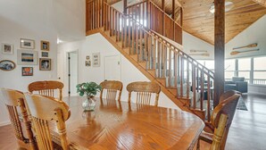 Un comedor con una mesa y sillas de madera, una escalera y vistas al exterior.