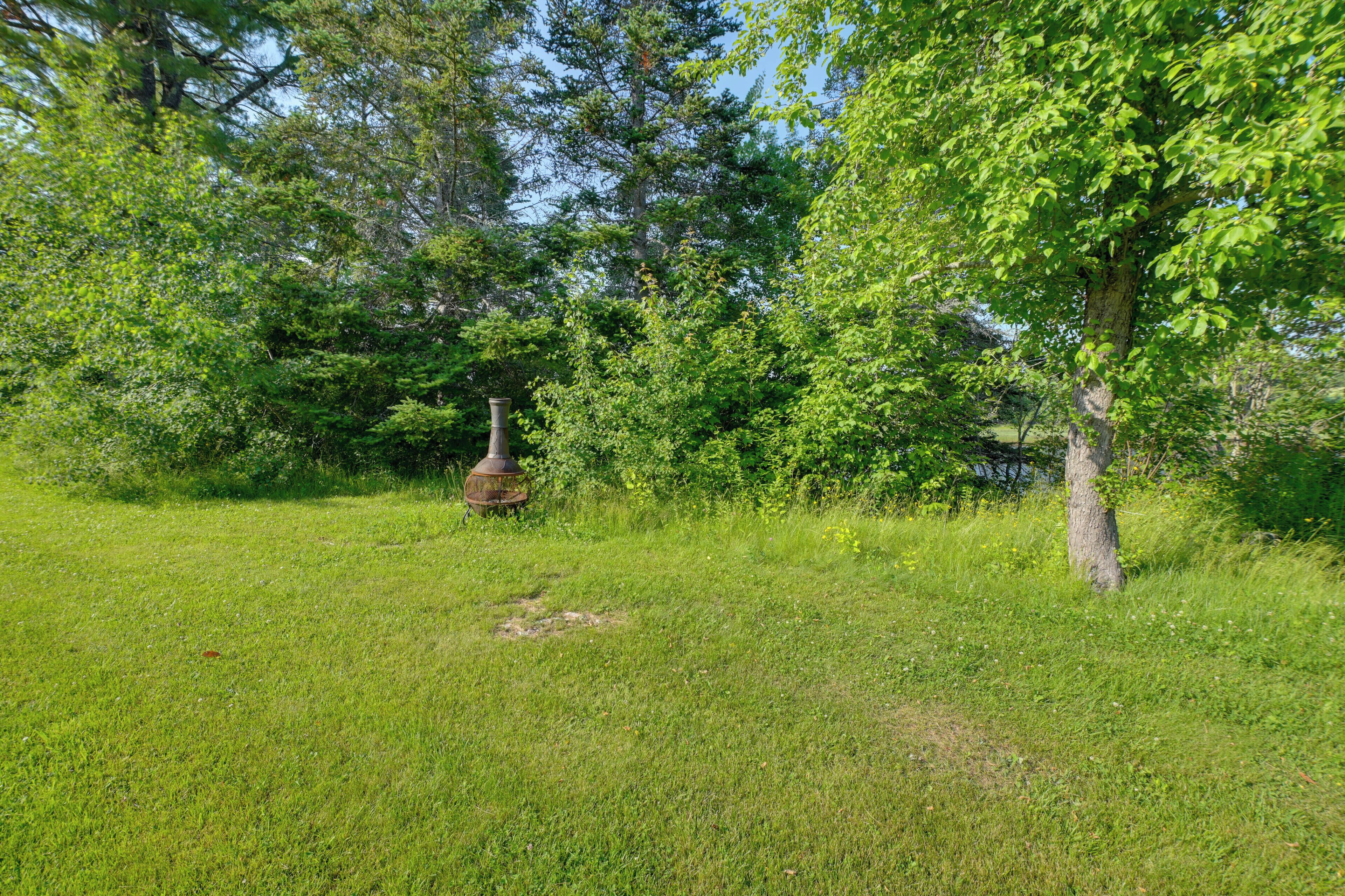 A grassy field with a large tree and a rusted metal structure.
