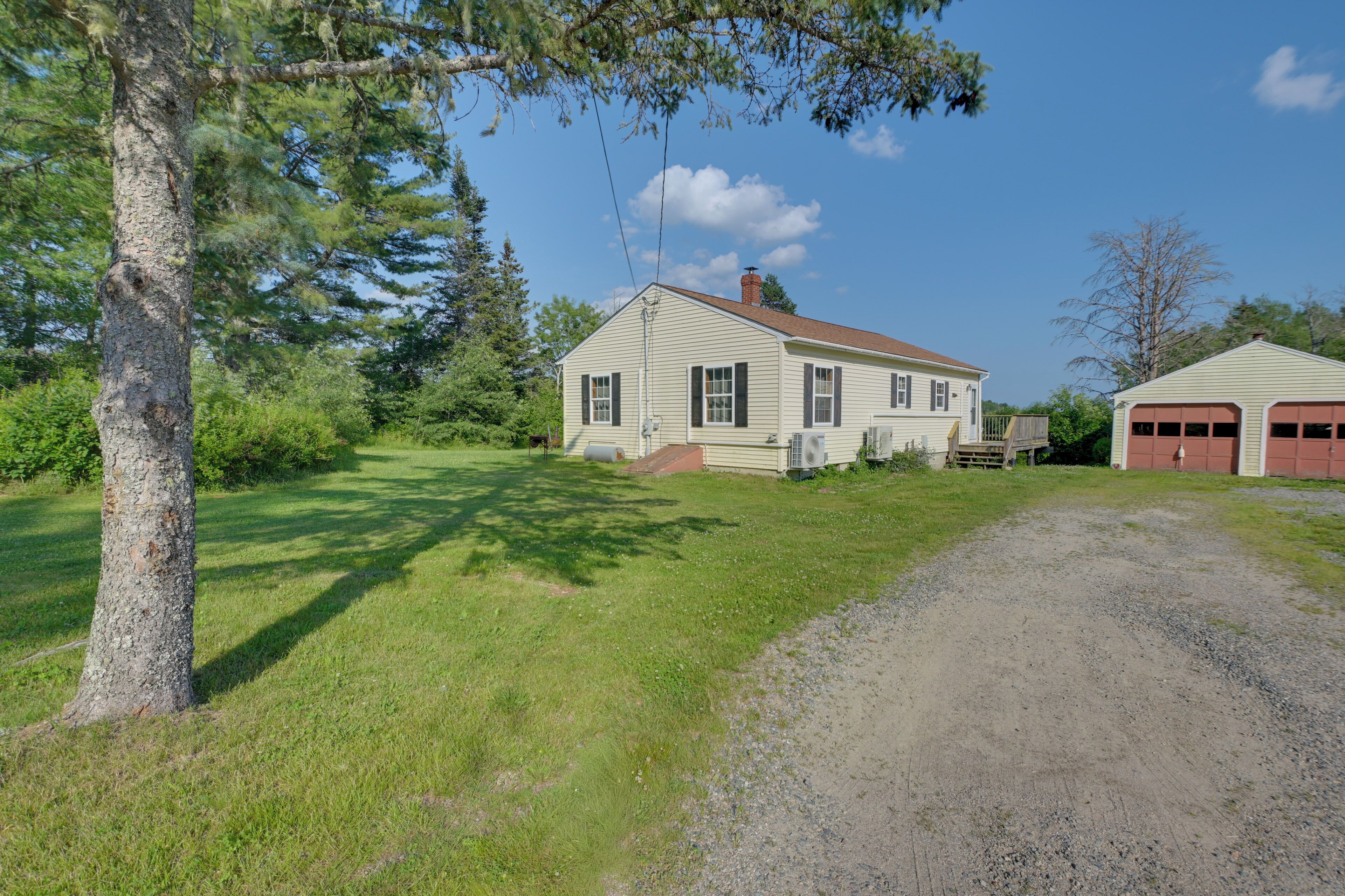 A two-story house with a front porch, a garage, and a gravel driveway.