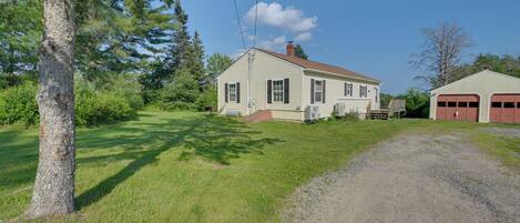 A two-story house with a front porch, a garage, and a gravel driveway.