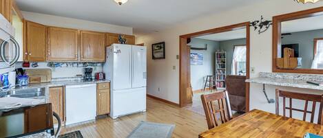 A kitchen with wooden cabinets, a refrigerator, a dining table, and a rug.