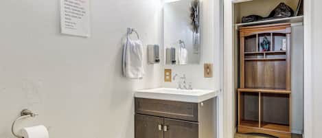 A bathroom with a sink, mirror, towel rack, and a sign instructing not to flush baby wipes.