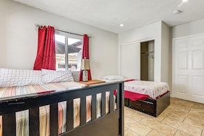 A bedroom with two beds, a window with red curtains, a bedside table with a lamp, and a closet. - Socal Launchpad: 3BR in Hawthorne, 4 Mi to Sofi! (Hawthorne)