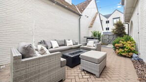 A patio with wicker furniture, a fire pit, and a brick floor. - Luxury home in Trilith steps from US Soccer Center, Pool, and Restaurants (Fayetteville)