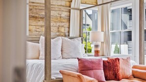 A bedroom with a four-poster bed, a window with curtains, and a sofa with cushions. - Luxury home in Trilith steps from US Soccer Center, Pool, and Restaurants (Fayetteville)