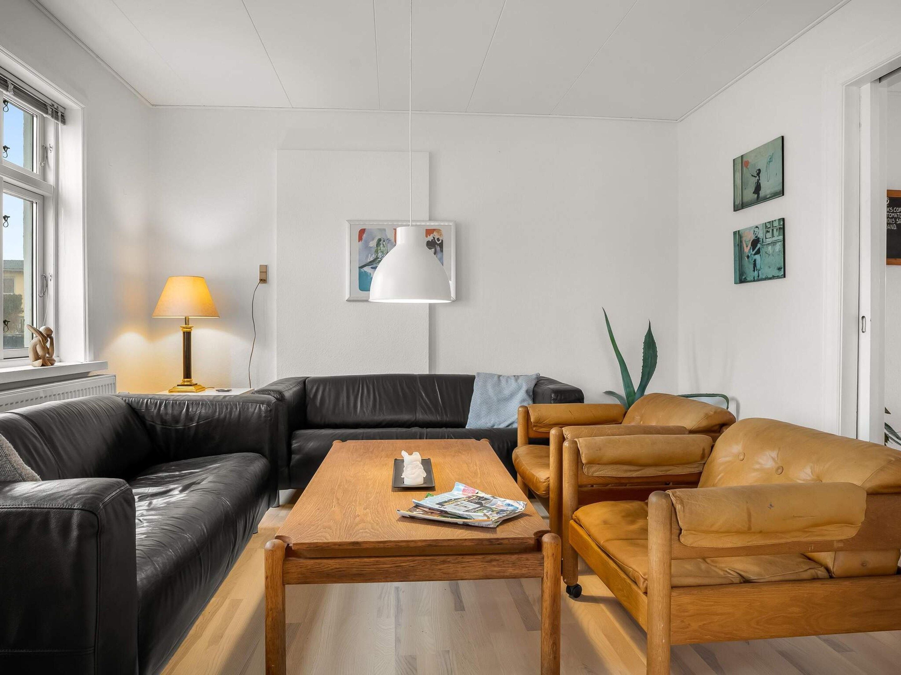 Una sala de estar moderna con un sofá de cuero negro, una mesa de centro de madera y un sillón de cuero amarillo.