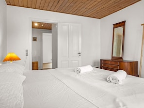 A hotel room with a bed, a dresser, a mirror, and a lamp. - 4 Star Holiday Home in Lokken (Lokken)