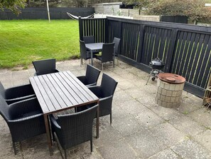 An outdoor patio with a table and chairs, a barbecue grill, and a trash can. - 4 Star Holiday Home in Lokken (Lokken)