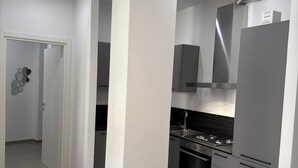 Une cuisine moderne dotée d’un îlot central, d’appareils électroménagers en acier inoxydable et de luminaires suspendus.