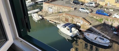 A view through a window of a marina with boats docked, buildings in the background, and a clear sky.