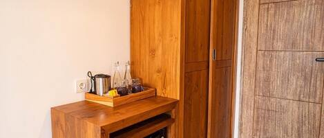 Un gabinete de madera con un microondas integrado, un pequeño estante con frascos y una puerta de madera.