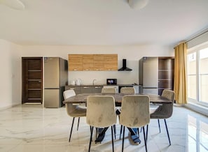 A modern kitchen with a dining table and chairs, built-in cabinets, and a large window. - One of a kind Home | Ensuite Bedrooms & Wi-Fi (Swieqi)