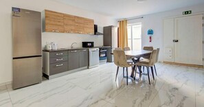 A modern kitchen with a dining area, stainless steel appliances, wooden cabinets, and a marble floor. - One of a kind Home | Ensuite Bedrooms & Wi-Fi (Swieqi)