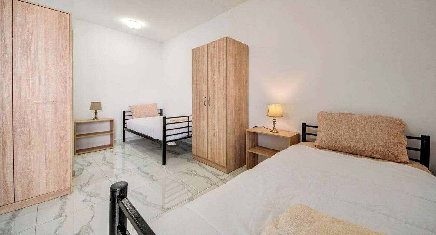 Une chambre à coucher comprenant un lit, une armoire, une table de chevet et un bureau.