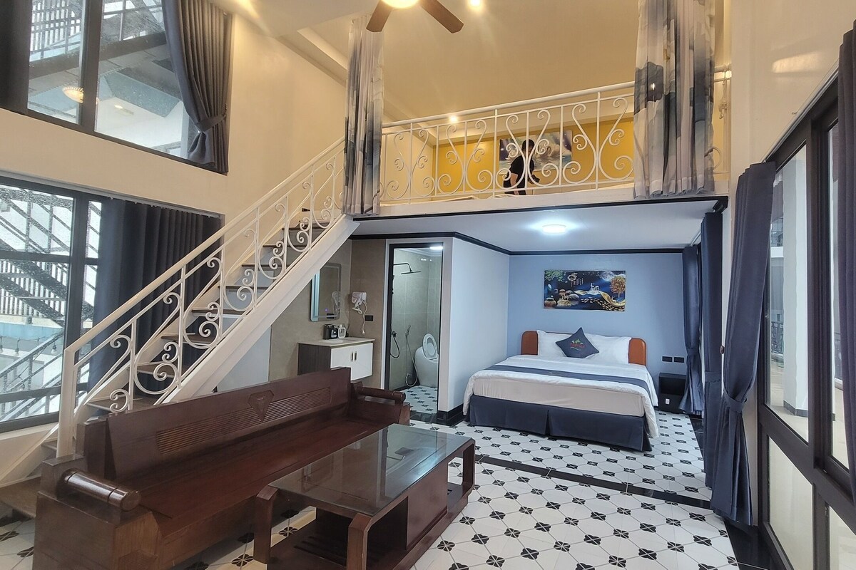 Een hotelkamer met een bed, een bureau, een stoel, een balkon en een trap.