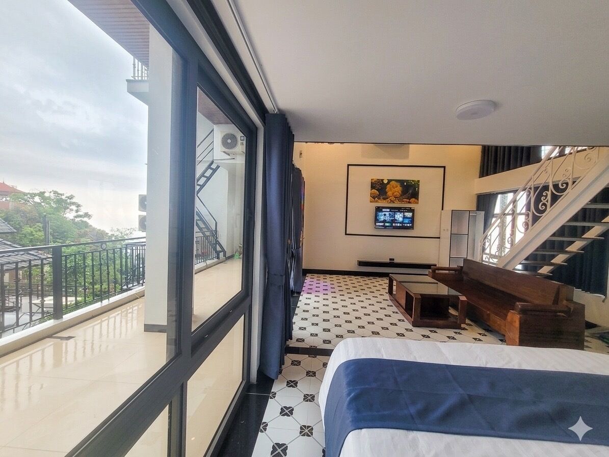 Ein Hotelzimmer mit Bett, Schreibtisch, Fernseher und einem Balkon mit Geländer.