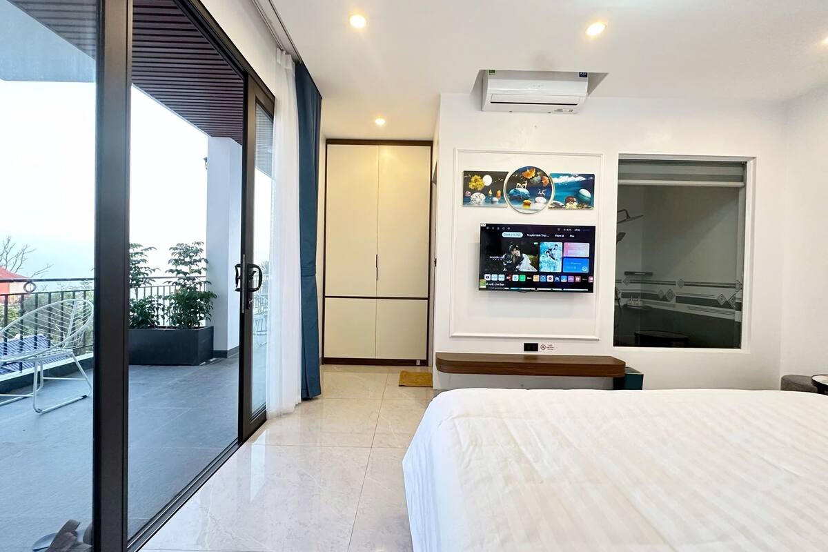 Ein modernes Hotelzimmer mit Balkon, einem an der Wand montierten Fernseher und einem großen Fenster.