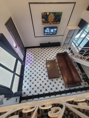 A room with a patterned floor, a television mounted on the wall, and a window with curtains. - Time Villa (Tam Dao)