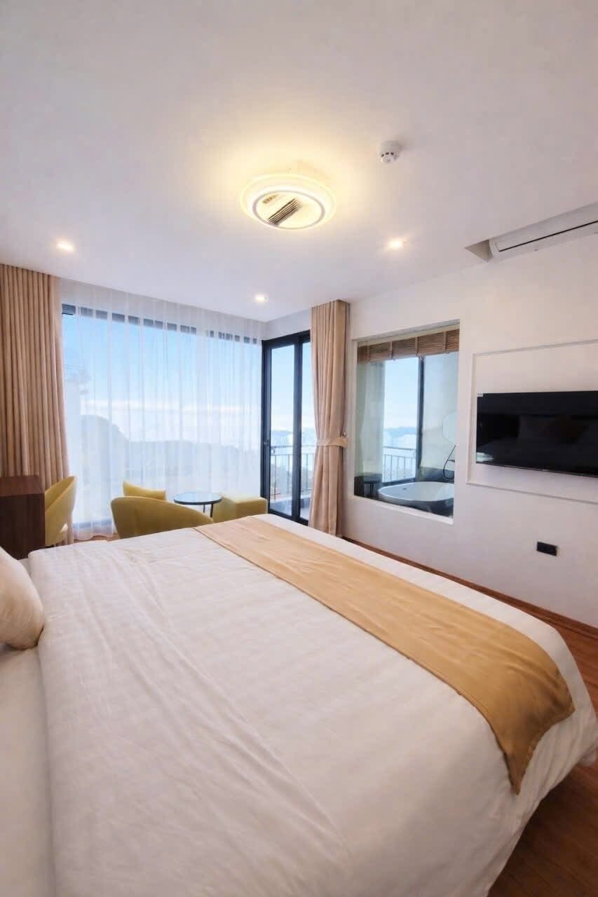 Ein Hotelzimmer mit einem großen Bett, einem an der Wand montierten Fernseher, einem Fenster mit Blick und einem kleinen Tisch mit Stühlen.