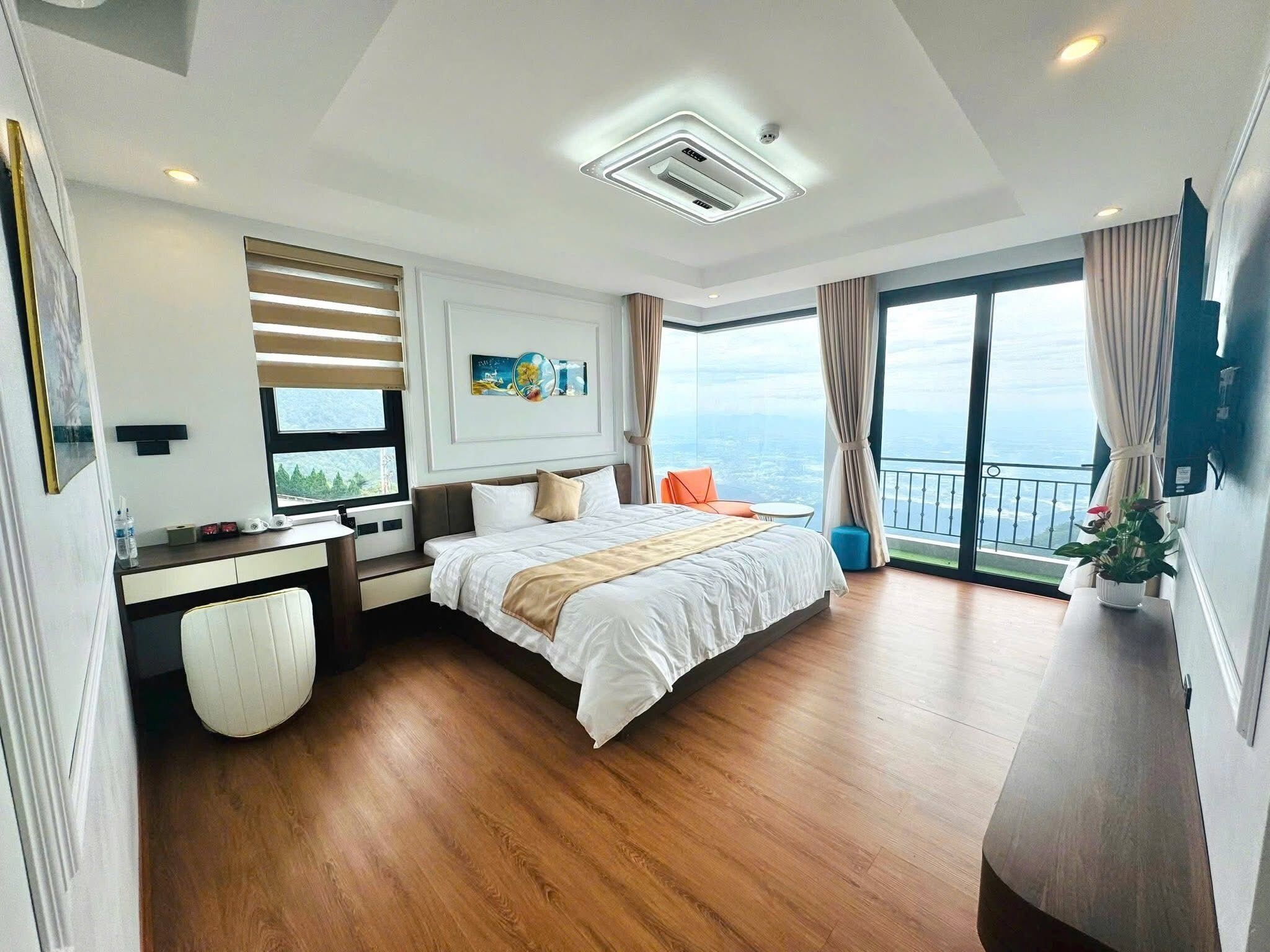 Ein modernes Hotelzimmer mit einem großen Bett, einem Schreibtisch mit Stuhl, einem kleinen Tisch und einem großen Fenster mit Ausblick.