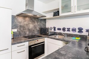 Et moderne køkken med mikroovn, brødrister, ovn og en bordplade af granit.
