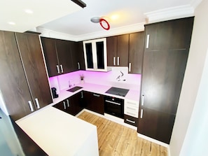 A modern kitchen with dark wood cabinets, a white countertop, and a built-in oven.