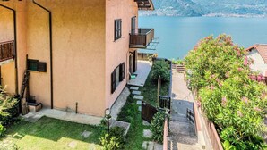 Um edifício com telhado ladrilhado, varanda e vista para um lago e montanhas.