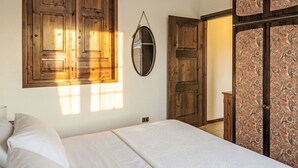 Quarto com cama, guarda-roupa de madeira e espelho.