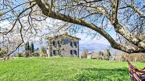 Une maison en pierre avec un champ verdoyant et un hamac.