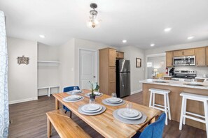 Una cocina moderna con una isla central, electrodomésticos integrados y un comedor con mesa y sillas de madera.