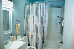 A bathroom with a shower curtain, toilet, sink, and a towel rack.