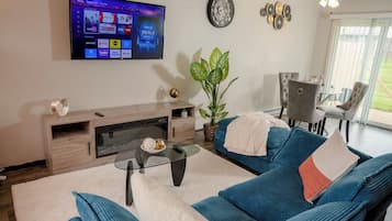 Un salon avec un téléviseur, un canapé, une table basse et une plante.