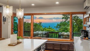 Una cocina con un ventanal que da a una terraza y vistas al cielo.