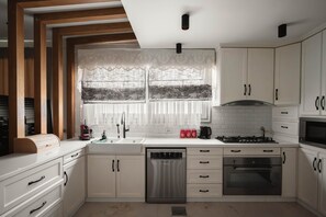 Eine moderne Küche mit weißen Schränken, einem Edelstahl-Geschirrspüler, einem Gasherd und einem eingebauten Backofen.