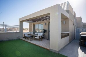 Terraço no telhado com deck de madeira, mobiliário para área externa e vista para a cidade.