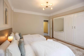 A bedroom with a large bed, bedside lamps, a ceiling light fixture, and a wardrobe.