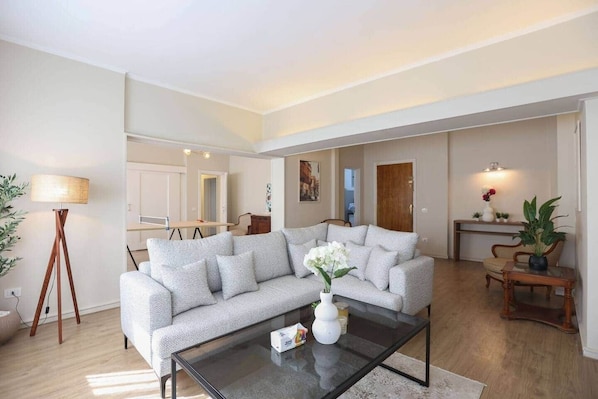A spacious living area with a sofa, coffee table, and a lamp.