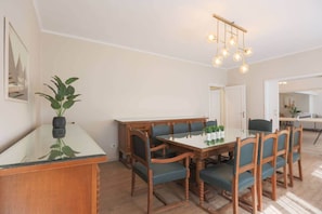 A dining area with a glass-top table, wooden chairs, and a hanging light fixture.