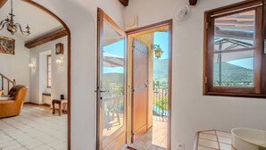 Une pièce dotée d’une porte en bois donnant sur un balcon avec vue sur la campagne.
