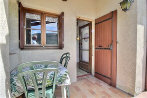 Un patio con una mesa y sillas, una puerta de madera y una ventana con vistas.