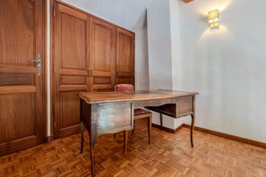 A room with a wooden floor, a desk with drawers, and a wardrobe with a door handle.