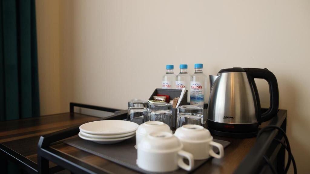 A hotel room's breakfast tray with plates, cups, a kettle, and bottled water.