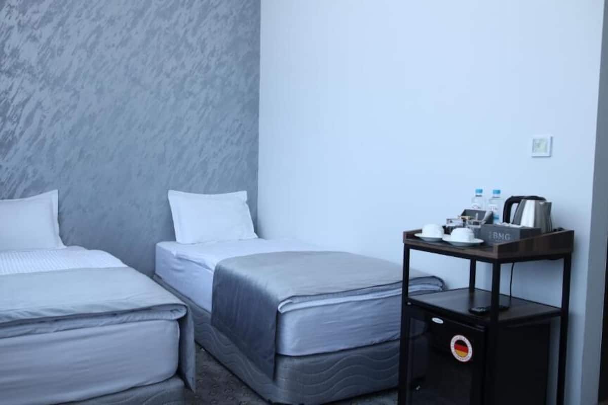 Una habitación de hotel con dos camas, una mesita con cafetera y un minibar.