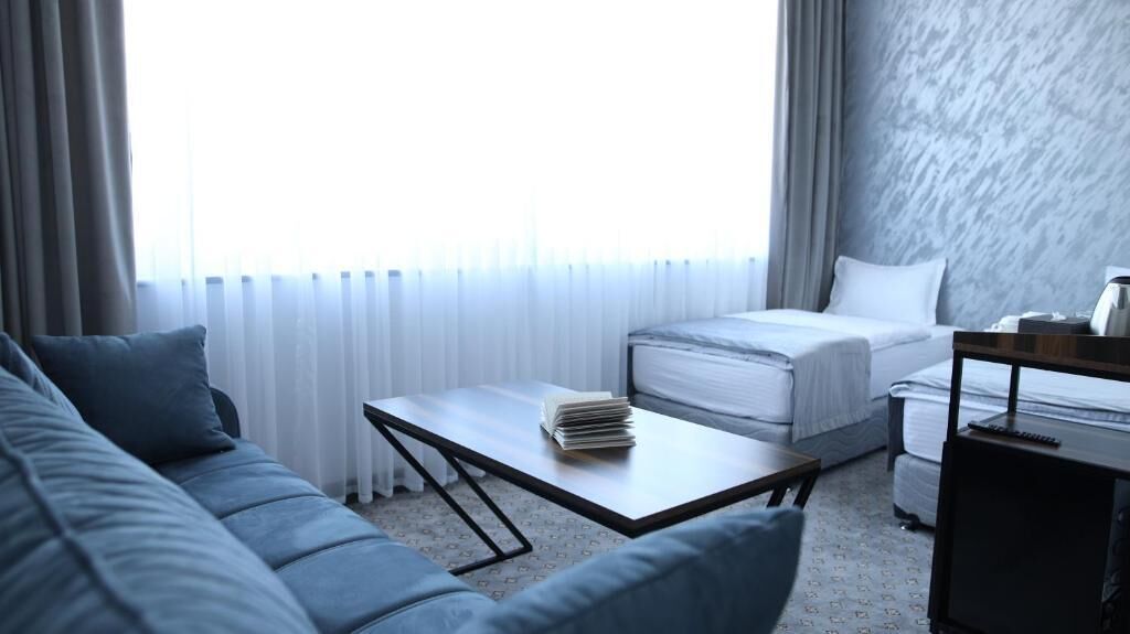 A hotel room with a bed, a sofa, a coffee table, and a desk.