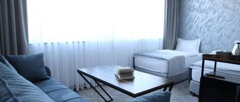 A hotel room with a bed, a sofa, a coffee table, and a desk.