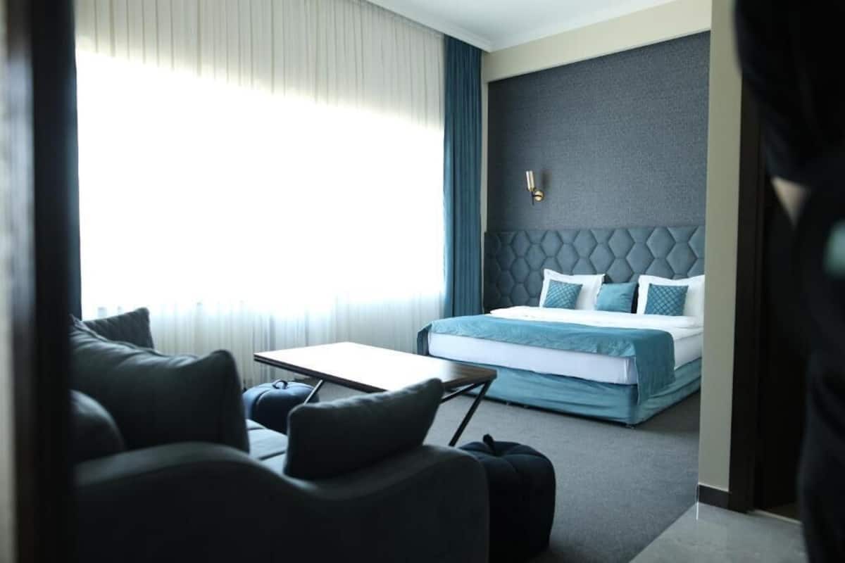 Una habitación de hotel moderna con cama, sofá, una mesita y vistas al exterior.