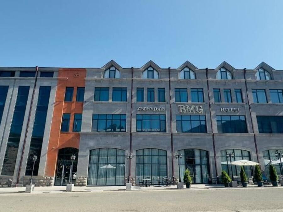 A multi-story hotel with a modern design, featuring large windows and a prominent 'BMG Hotel' sign.