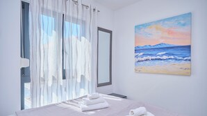 A bedroom with a bed, a painting of a beach scene, and a window with sheer curtains. - Ray Holiday Apartment (Okrug Gornji)