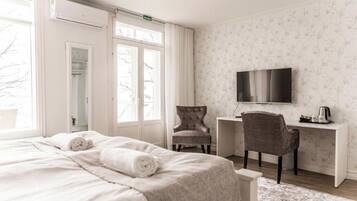 A hotel room with a bed, a desk, a chair, a TV, and a window.