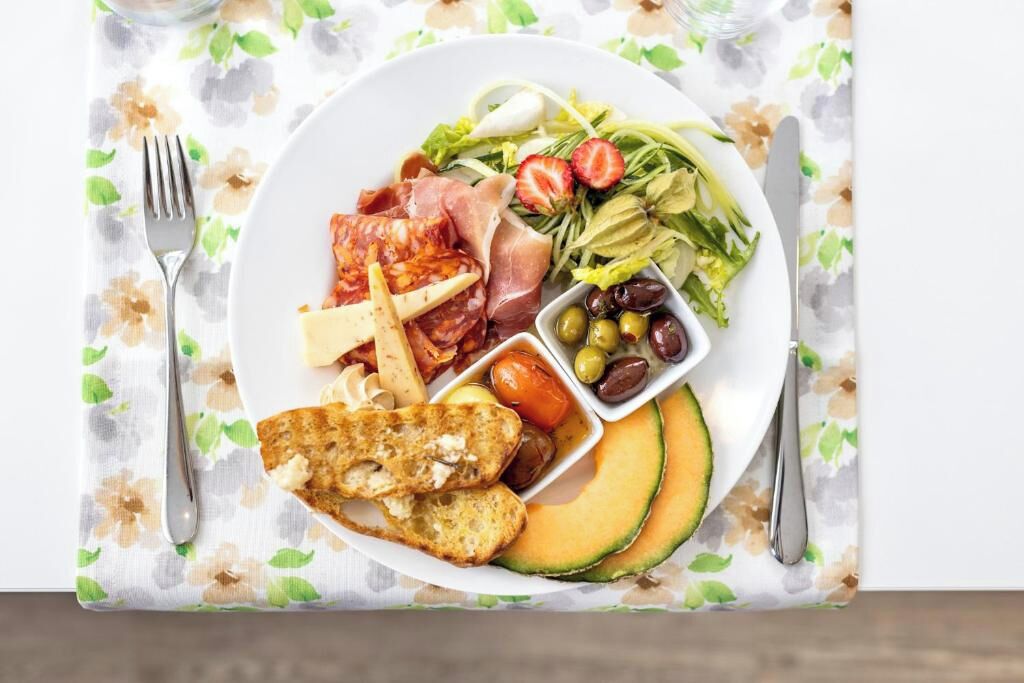 A plate with various foods including meats, cheese, olives, and vegetables.